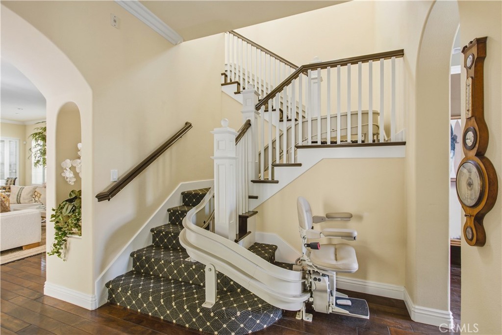 Staircase with patterned carpeted treads, white painted risers and balusters, dark wood handrails, installed stair-lift - 21322 Balerma, Huntington Beach CA 92648 - photo 41