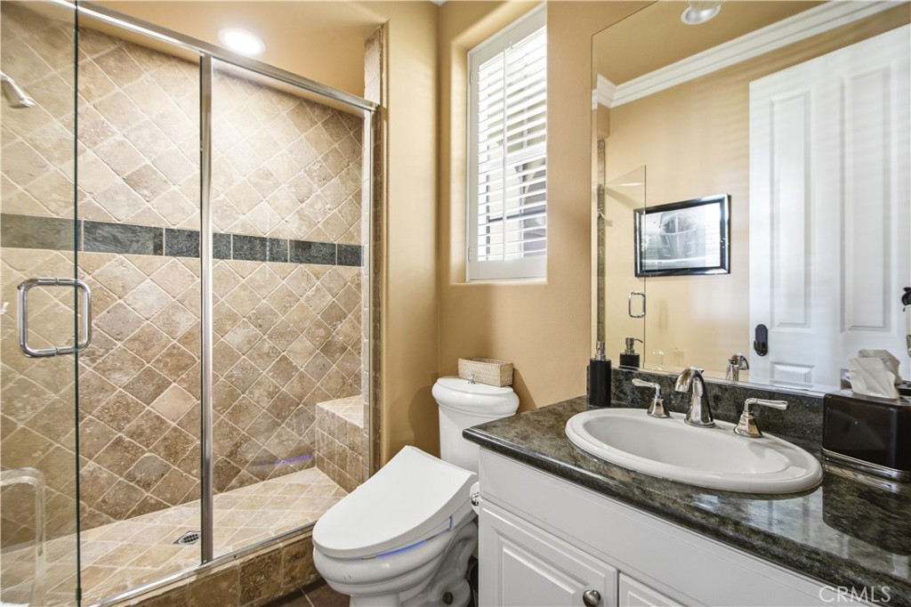 Main floor bathroom with glass door walk-in shower with stone like tile, white vanity with granite countertop, toilet, l - 21322 Balerma, Huntington Beach CA 92648 - photo 42