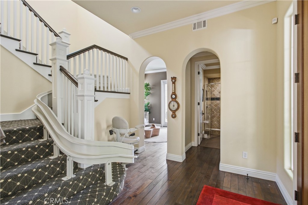 Staircase with patterned carpeted treads, white painted risers and balusters, dark wood handrails, installed stair-lift - 21322 Balerma, Huntington Beach CA 92648 - photo 43
