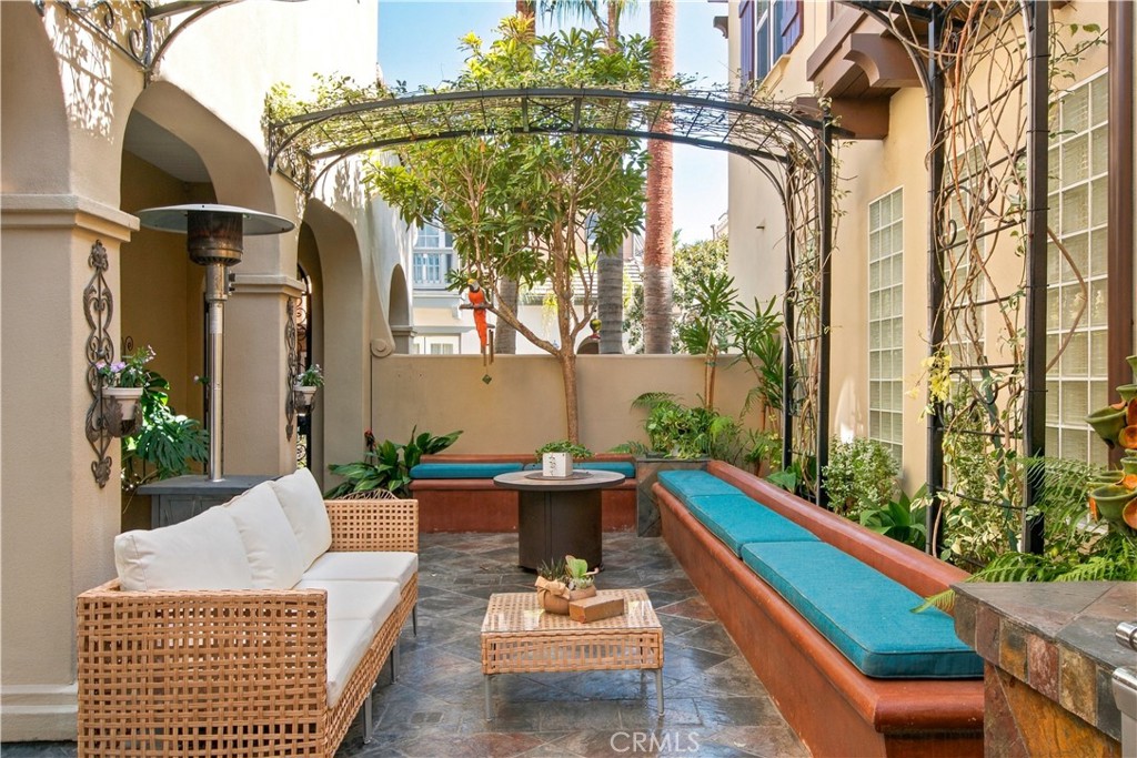 Enclosed courtyard with stone tile flooring, metal trellises with climbing vines, built in seating and archways. - 21322 Balerma, Huntington Beach CA 92648 - photo 46