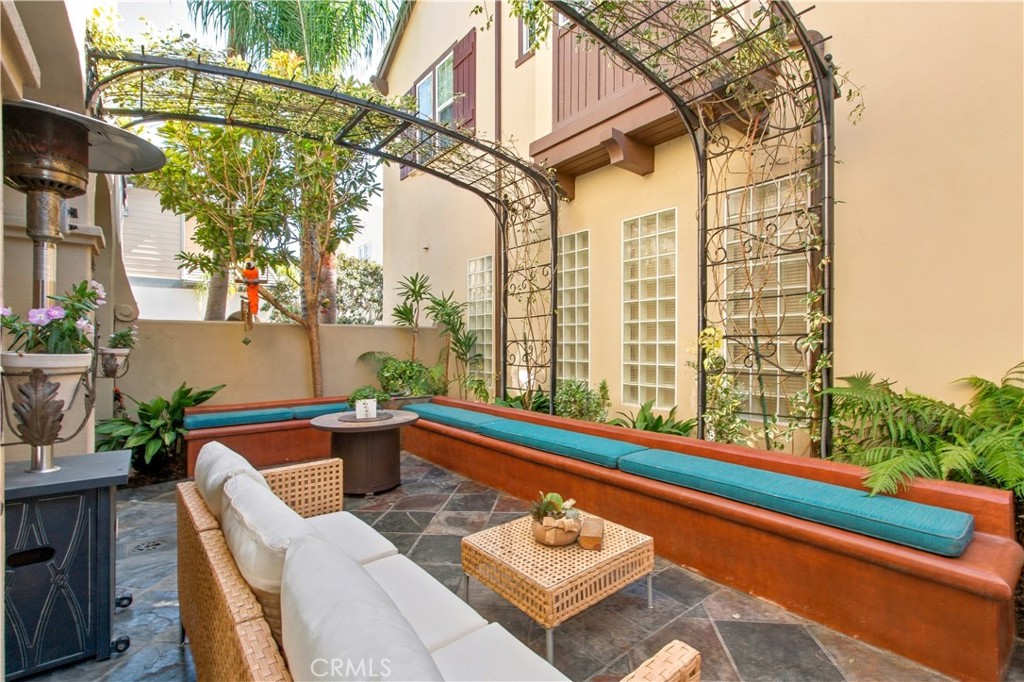 Enclosed courtyard with stone tile flooring, metal trellises with climbing vines and built in seating. - 21322 Balerma, Huntington Beach CA 92648 - photo 48