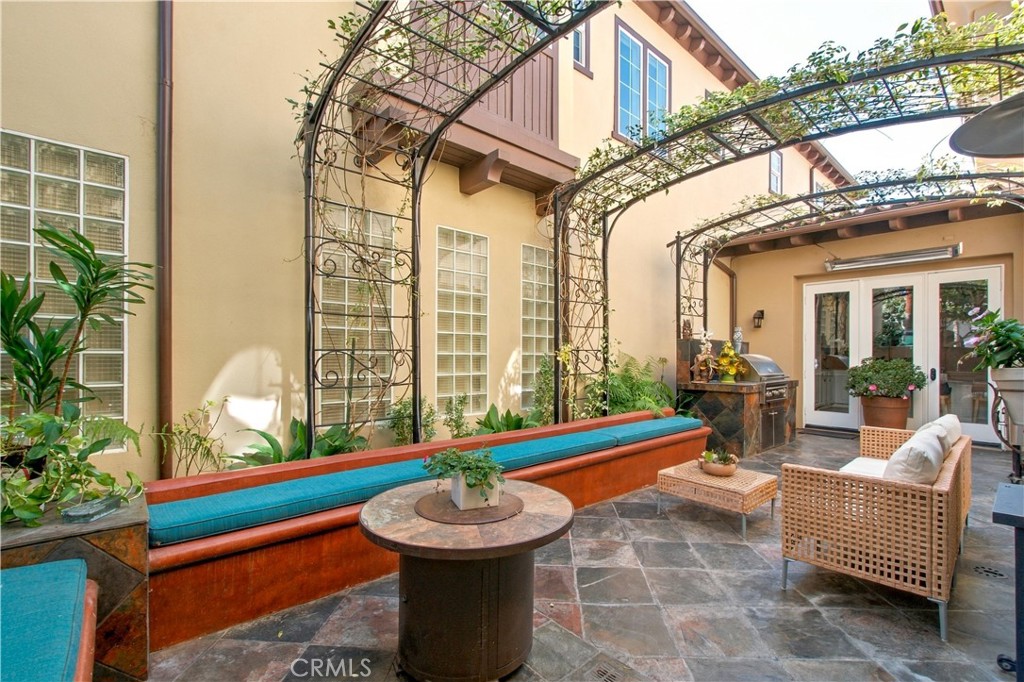Enclosed courtyard with stone tile flooring, metal trellises with climbing vines, built in seating and custom-built outd - 21322 Balerma, Huntington Beach CA 92648 - photo 50
