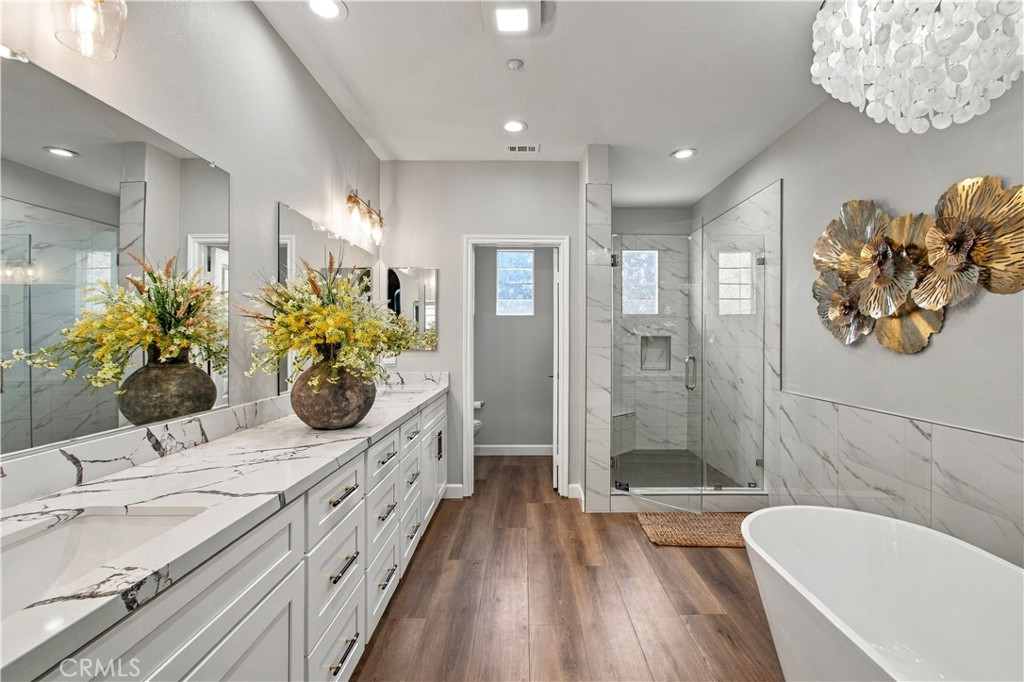Spa-inspired bath with dual sinks, seated vanity, deep soaking tub, and separate glass-enclosed shower. - 21335 Cieza, Huntington Beach CA 92648 - photo 37