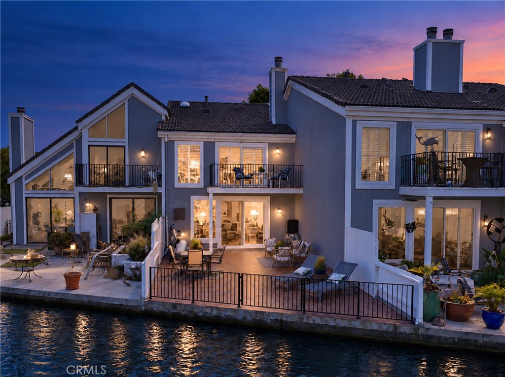 As evening falls, the home glows with warm, inviting ambiance, beautifully complementing the shimmering silver waters. - 3631 Windspun Drive Drive, Huntington Beach CA 92649 - photo 2