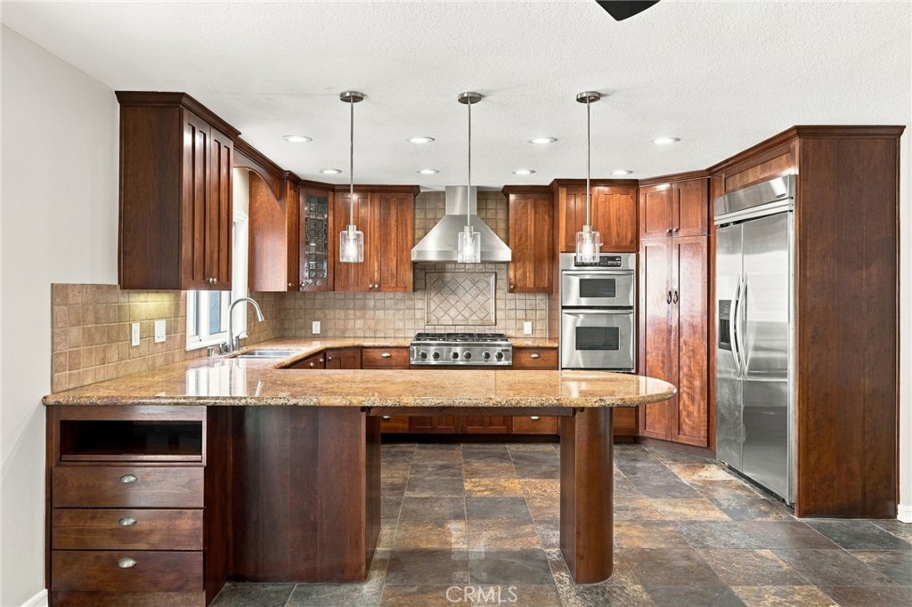 Well-appointed kitchen features granite countertops, cherrywood-tone shaker cabinetry, and peninsula seating. - 803 Frankfort Avenue, Huntington Beach CA 92648 - photo 18