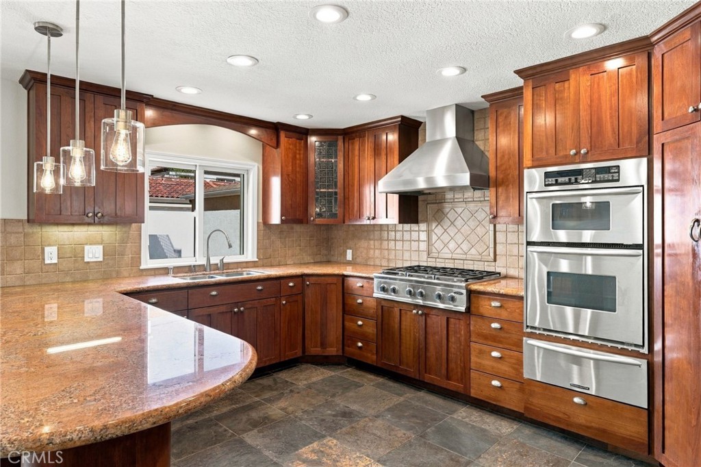 Granite countertops, tile backsplash, stainless appliances, and abundant cabinetry complete the kitchen. - 803 Frankfort Avenue, Huntington Beach CA 92648 - photo 23