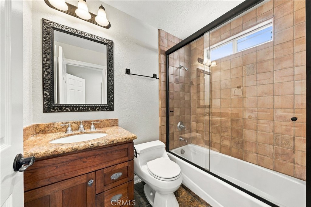 Downstairs full bathroom features a tub/shower, tile surround, granite countertop, and shaker-style vanity. - 803 Frankfort Avenue, Huntington Beach CA 92648 - photo 27