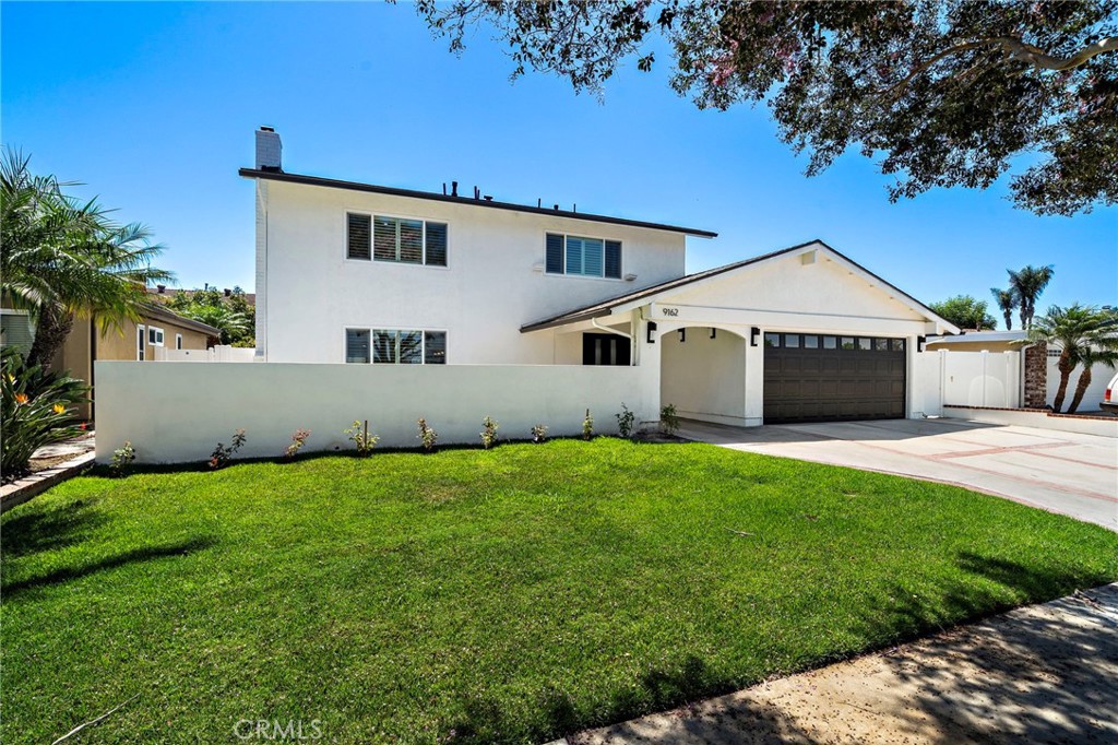 Inviting front exterior framed by lush lawn, mature landscaping and a wide driveway. - 9162 Brabham Drive, Huntington Beach CA 92646 - photo 2