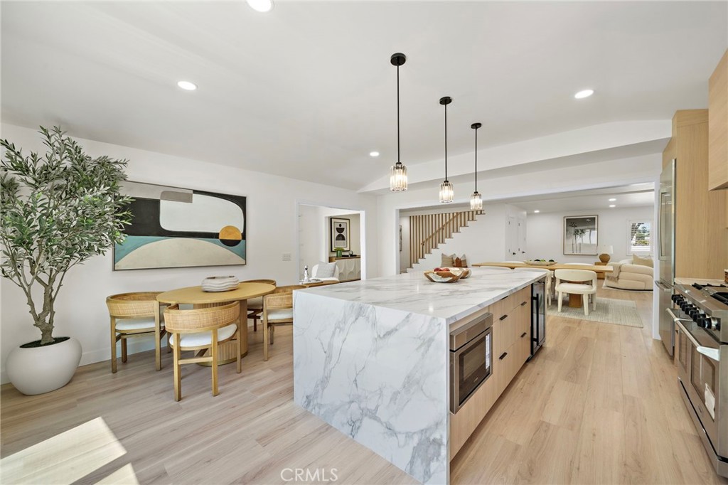 Wide kitchen view highlights the waterfall-edge island, modern pendant lights and easy flow into the dining area. - 9162 Brabham Drive, Huntington Beach CA 92646 - photo 25