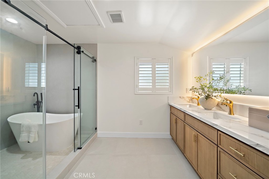 Downstairs Primary bathroom features a long dual-sink vanity, designer finishes and a large glass-enclosed shower. - 9162 Brabham Drive, Huntington Beach CA 92646 - photo 33