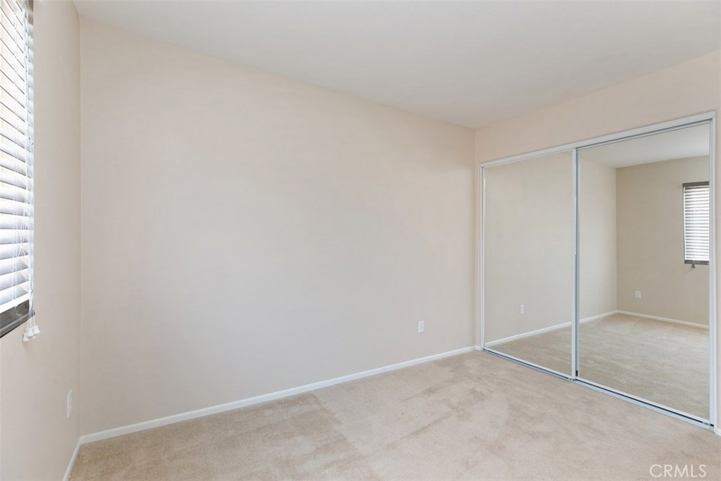 Secondary bedroom, with mirrored closet and wood-blind shades. *flooring to be updated with LVP prior to move-in. - 10 New Market, Irvine CA 92602 - photo 12
