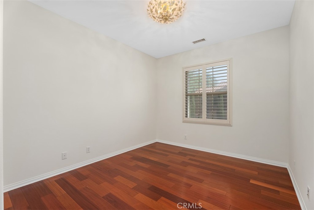 Second bedroom with custom light fixture, hardwood floors, and plantation shutters. - 117 Gemstone, Irvine CA 92620 - photo 19