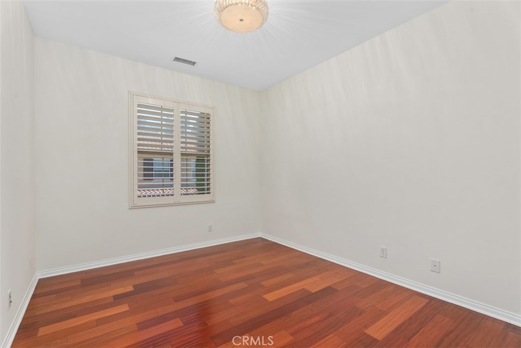 Third bedroom with custom light fixture, hardwood floors, and plantation shutters. - 117 Gemstone, Irvine CA 92620 - photo 20