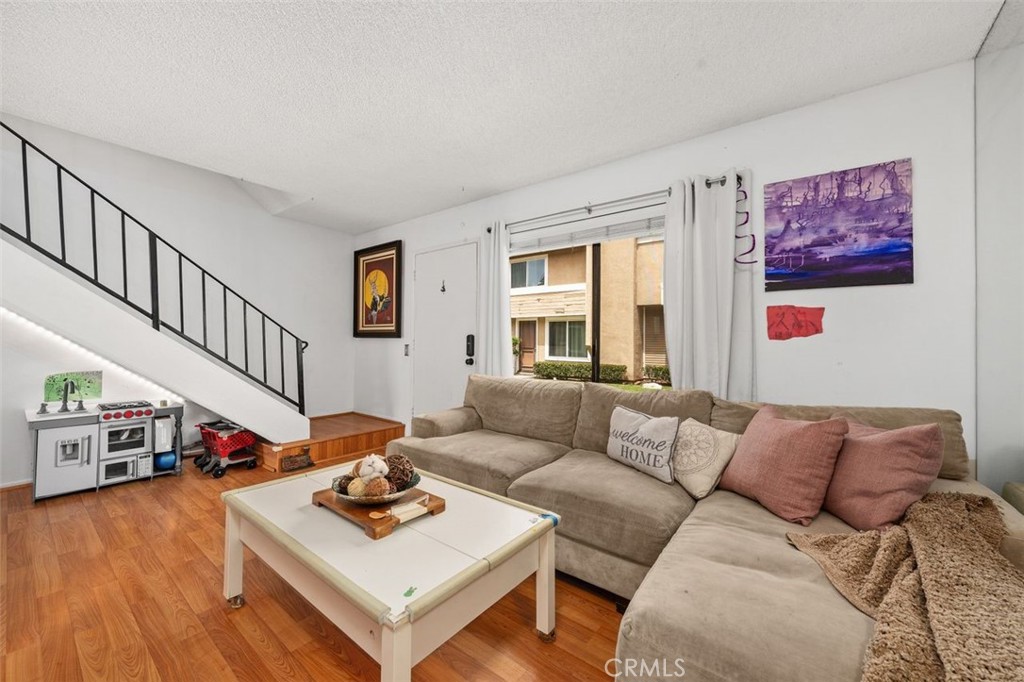 Living room with full mirrored wall and wrought-iron staircase railing. - 14 Greenleaf, Irvine CA 92604 - photo 5