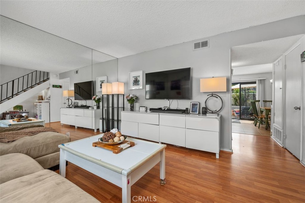 Living room with full mirrored wall and view toward the kitchen and dining area. - 14 Greenleaf, Irvine CA 92604 - photo 8