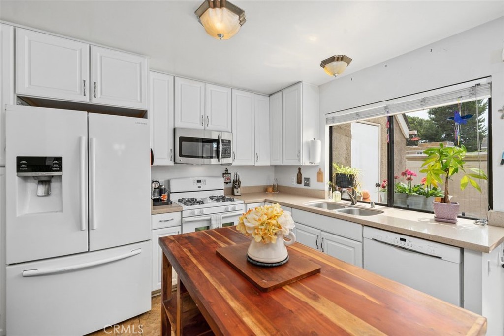 Updated kitchen with white cabinetry, quartz countertops, center island, and adjacent dining area. - 14 Greenleaf, Irvine CA 92604 - photo 13