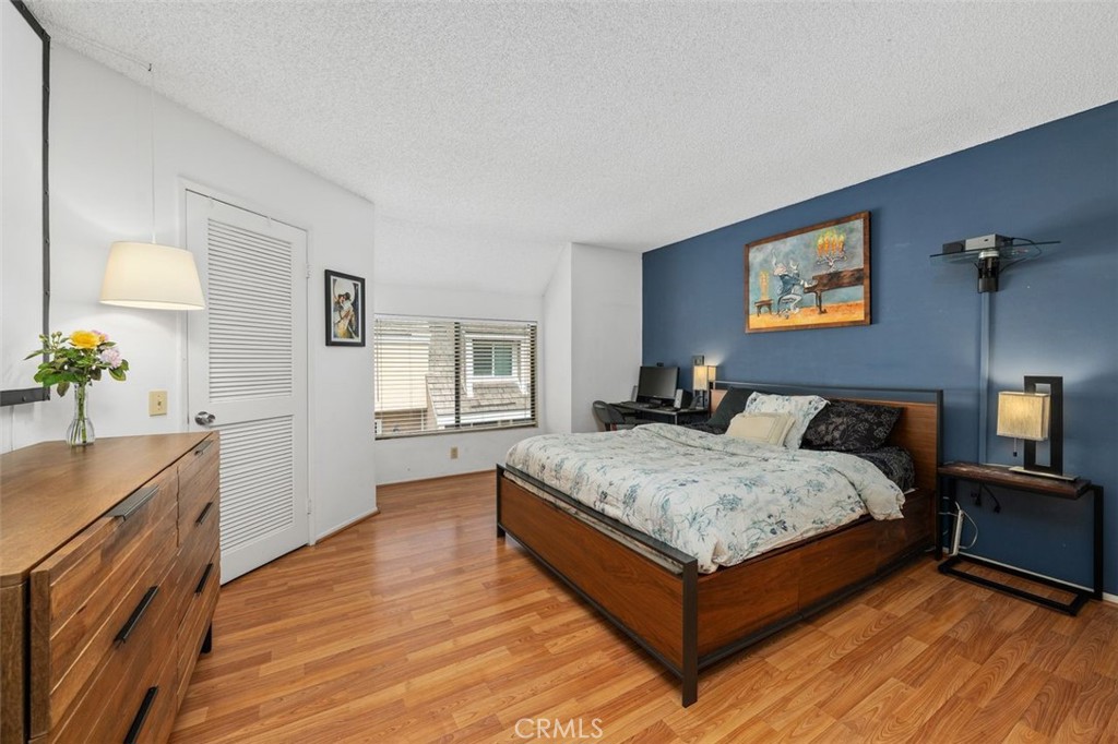 Primary bedroom with laminate wood-look flooring and contrasting accent wall. - 14 Greenleaf, Irvine CA 92604 - photo 18