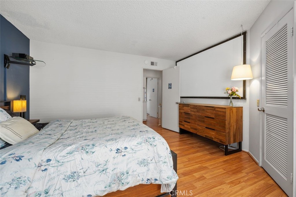 Primary bedroom with walk-in closet and laminate wood-look flooring. - 14 Greenleaf, Irvine CA 92604 - photo 21