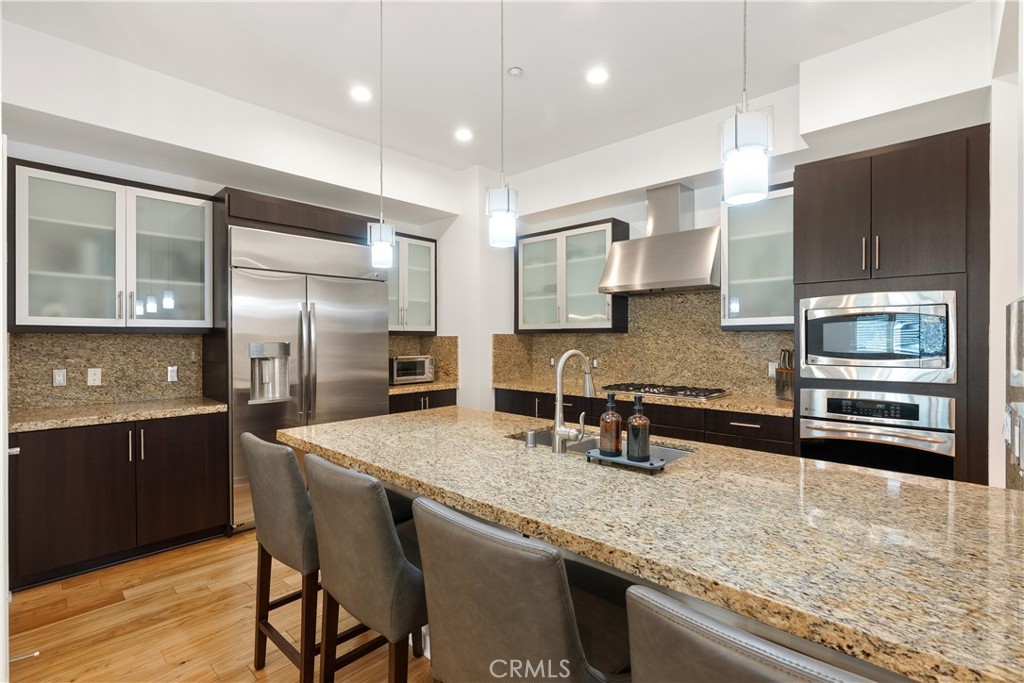 Beautifully updated kitchen with rich cabinetry, stone countertops, and generous prep space. - 21 Gramercy 102, Irvine CA 92612 - photo 7