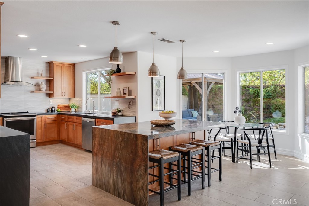 Updated kitchen features abundant cabinetry, a large center island with seating, contemporary backsplash, open shelving, - 21 Rhode Island, Irvine CA 92606 - photo 8