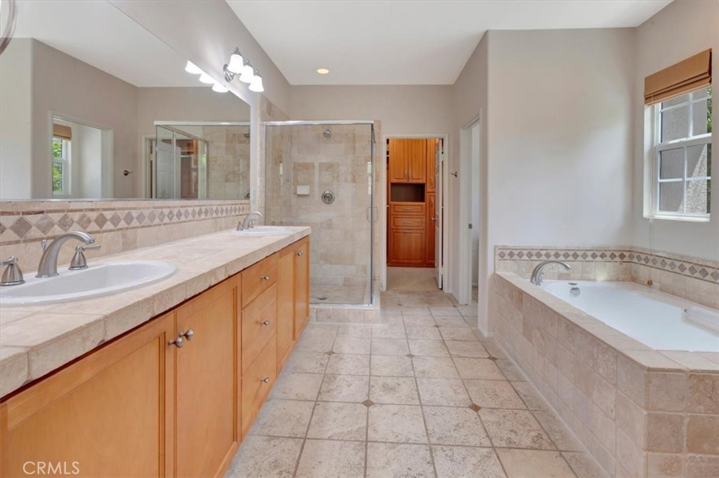 Spa-like primary bathroom with dual sinks, dressing table area to the right off-screen, soaking tub with VIEWS, walk-in - 47 Canopy, Irvine CA 92603 - photo 19