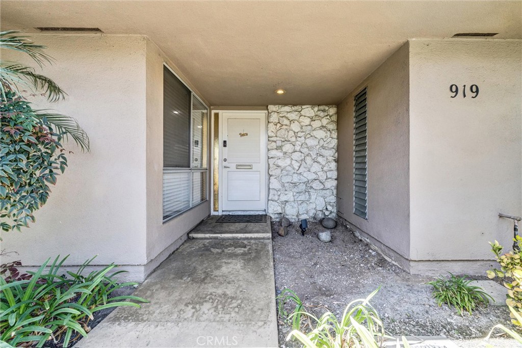 Covered front entry featuring a stone accent wall, large window, and walkway leading to the front door. - 919 Glencliff, La Habra CA 90631 - photo 2
