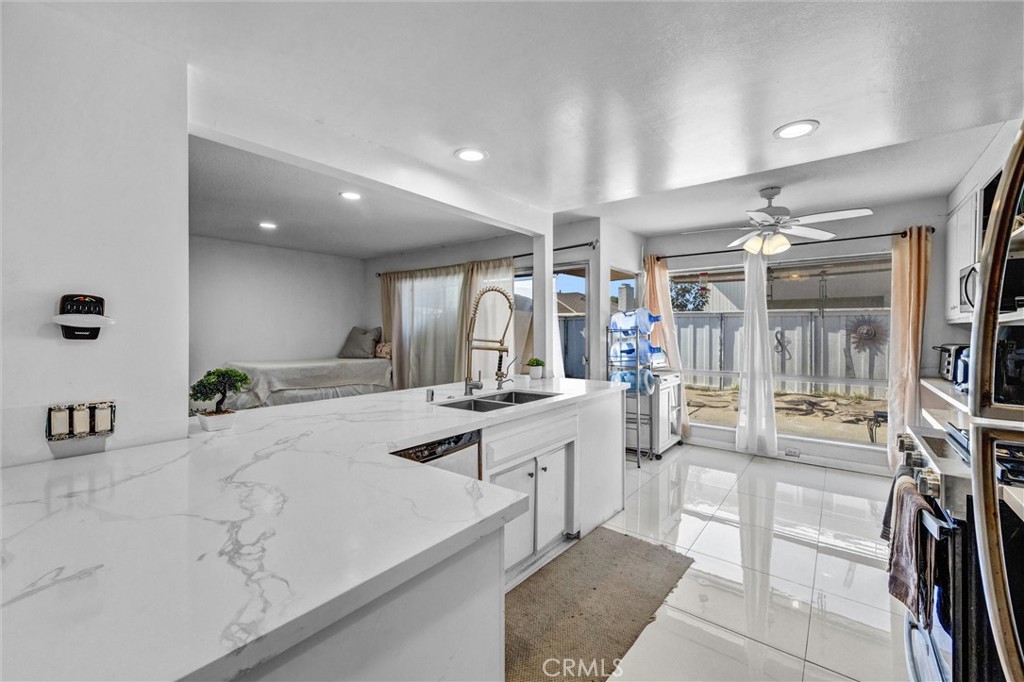 Remodeled kitchen with marble-look countertops, white cabinetry, and a stainless steel sink. - 919 Glencliff, La Habra CA 90631 - photo 3