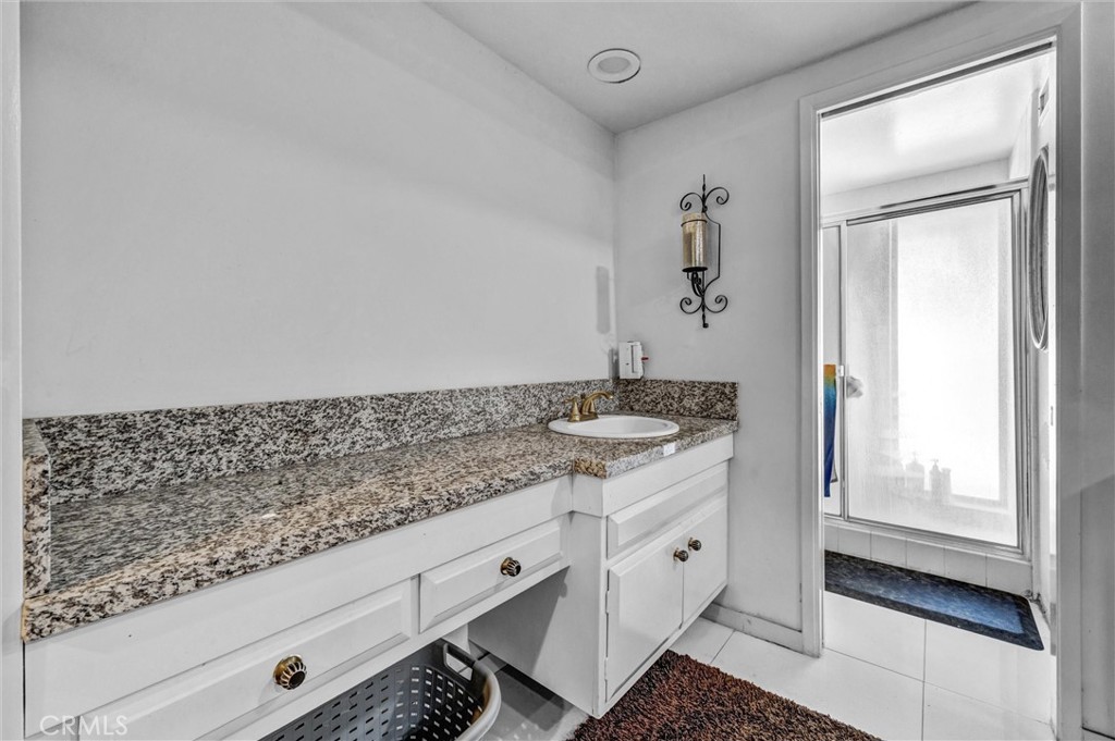 Granite countertop, white vanity cabinetry, tile flooring, and a skylight providing natural light. - 919 Glencliff, La Habra CA 90631 - photo 8