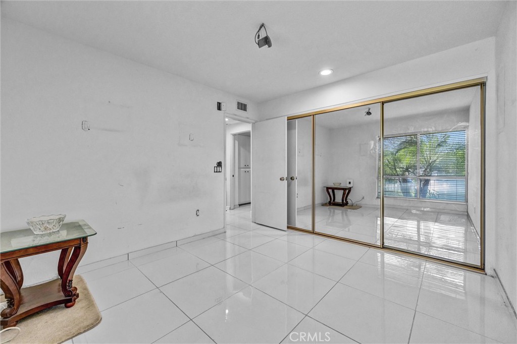 Spacious bedroom featuring tile flooring, mirrored closet doors, and recessed lighting. - 919 Glencliff, La Habra CA 90631 - photo 10