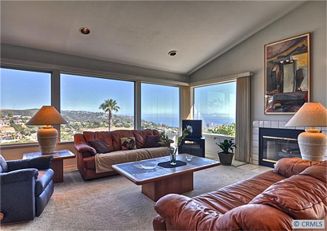 Living room looking southwest, showing part of panoramic canyon and ocean view through window, fireplace to right. - 1535 CARIBBEAN Way, Laguna Beach CA 92651 - photo 1