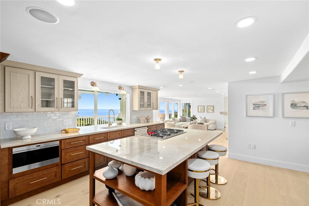 A modern kitchen anchored by Taj Mahal quartzite and a central island features a Wolf cooktop, double ovens, and a Sub-Z - 1675 Tahiti Avenue, Laguna Beach CA 92651 - photo 4