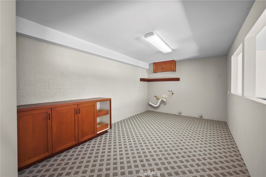 Bonus room off the garage with brand new carpeting, a built-in cabinet for storage and laundry facilities at the far end - 21771 Ocean Vista Drive 29, Laguna Beach CA 92651 - photo 28