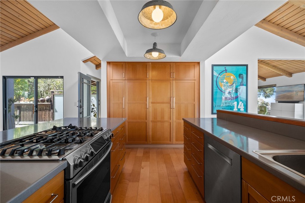 An open-concept gourmet kitchen features wood and glass cabinetry, a spacious pantry, solid-surface countertops. - 28862 Top of the World Drive, Laguna Beach CA 92651 - photo 26