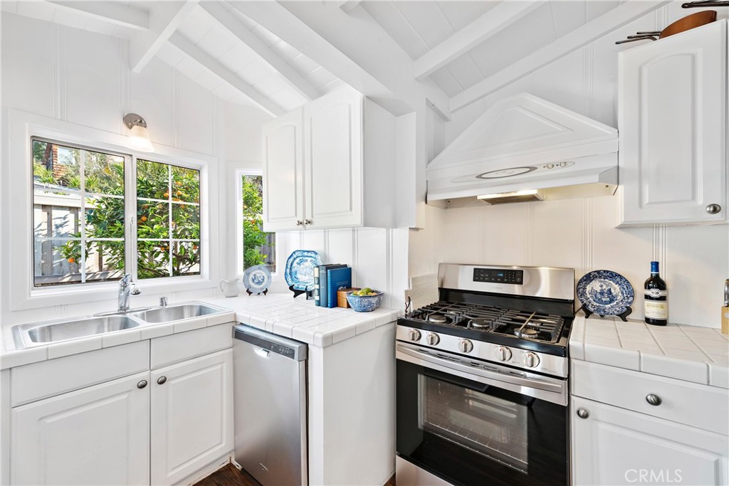 Kitchen with wood floors, high pitched beamed ceiling. Stainless range and dishwasher. Window opens to the private, encl - 31521 Summit Road, Laguna Beach CA 92651 - photo 8