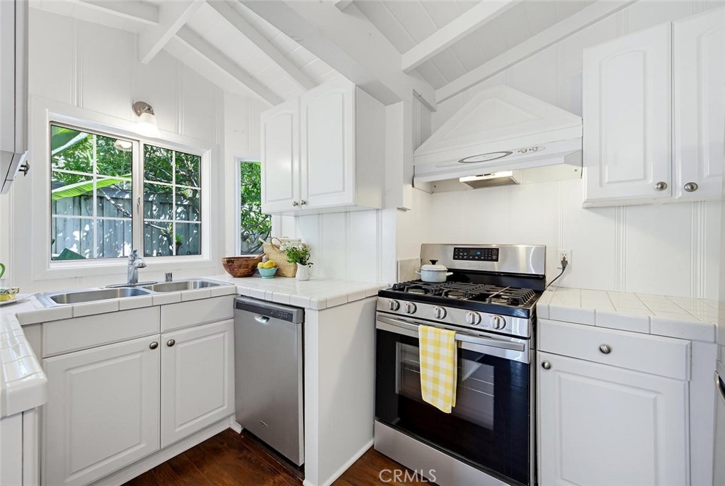 Kitchen with wood floors, high pitched beamed ceiling, stainless range and dishwasher. Window opens to the private, encl - 31521 Summit Road, Laguna Beach CA 92651 - photo 9