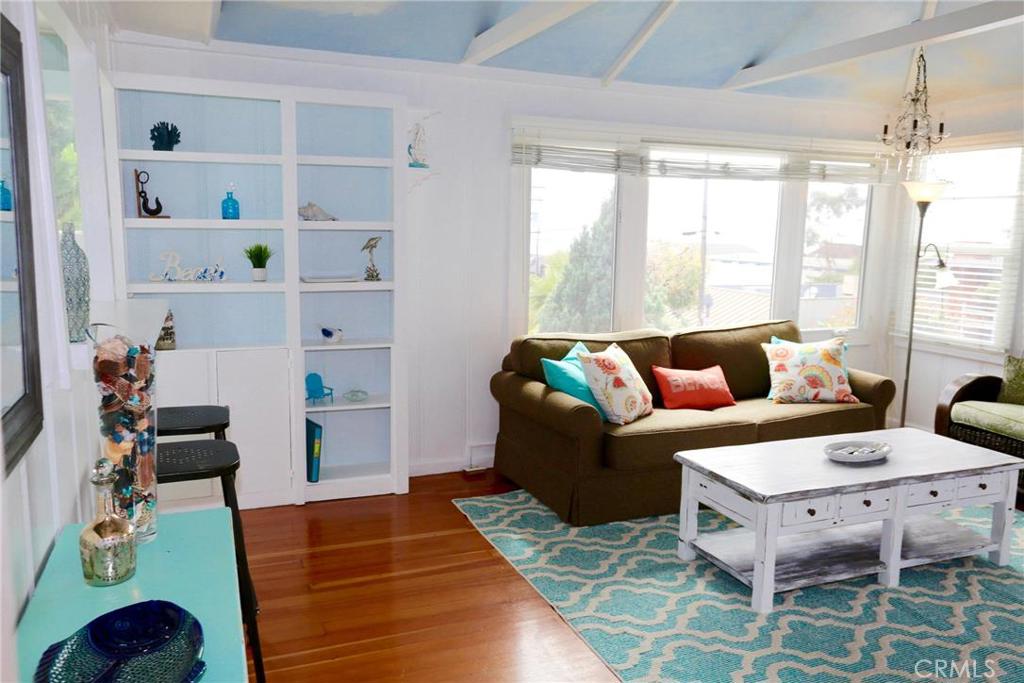 Spacious living room with ocean view, hardwood flooring, built in shelving, and kitchen. - 31692 3rd Avenue Upper, Laguna Beach CA 92651 - photo 1