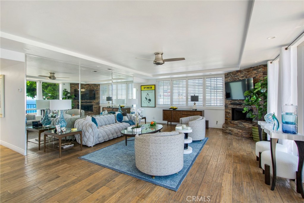 View from dining area towards living room with large wall mirrors, plantation shutters, stacked-stoned fireplace, recess - 31731 Seacove, Laguna Beach CA 92651 - photo 21