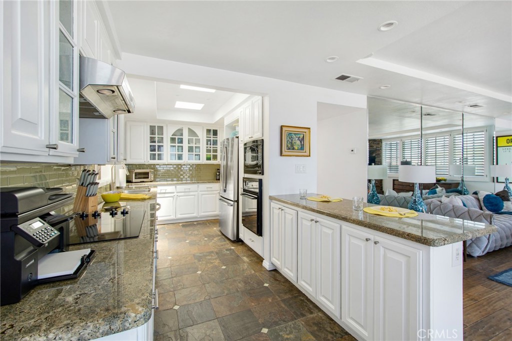 Updated kitchen with white cabinetry, granite countertops, glass tile backsplash, stainless-steel Refrigerator, recessed - 31731 Seacove, Laguna Beach CA 92651 - photo 32