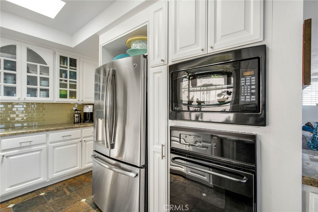 Closer view of updated kitchen with white cabinetry, glass tile backsplash, stainless-steel Refrigerator. - 31731 Seacove, Laguna Beach CA 92651 - photo 34