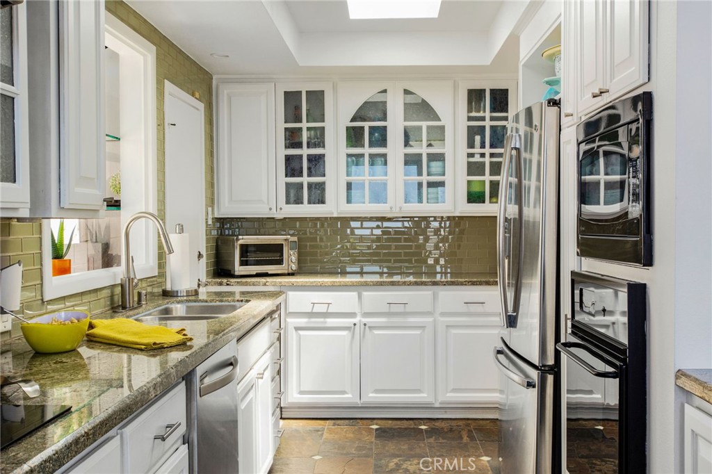 Another view of updated kitchen with white cabinetry with decorative glass-front accents, granite countertops, glass til - 31731 Seacove, Laguna Beach CA 92651 - photo 36