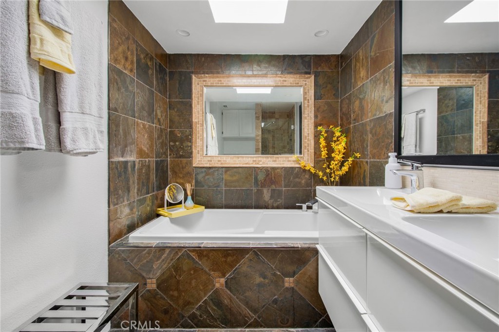 Primary EN-Suite bathroom with deep soaking tub with natural stone tile, vanity,mirrors, recessed lighting, and a skylig - 31731 Seacove, Laguna Beach CA 92651 - photo 42