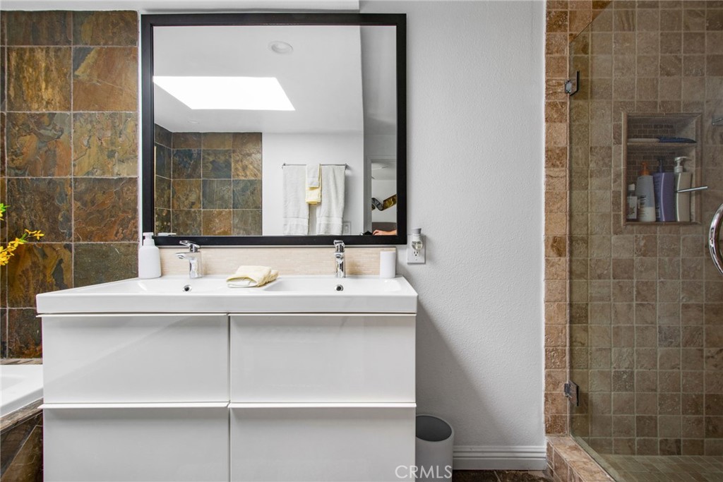 Primary bathroom with vanity, mirror deep soaking tub on one side and walk in shower on the other. - 31731 Seacove, Laguna Beach CA 92651 - photo 43