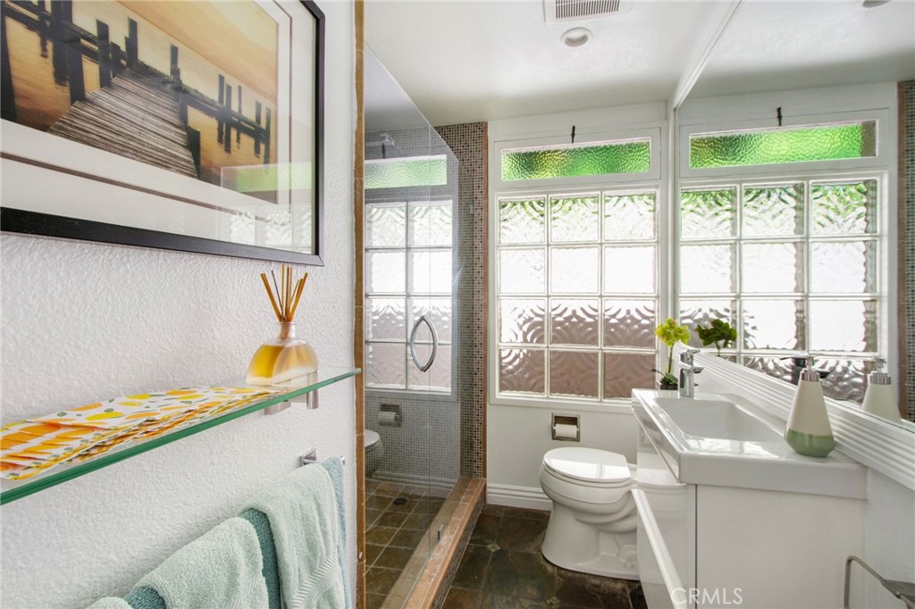 Guest bathroom view including textured glass block windows, tile floors, modern sink, large vanity mirror and glass door - 31731 Seacove, Laguna Beach CA 92651 - photo 47