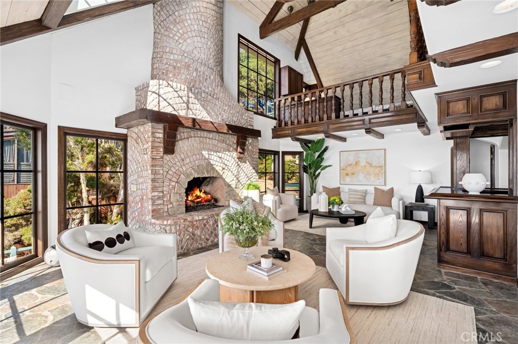The living room, anchored by an impressive double-height fireplace, opens to an oversized deck that appears to float abo - 31971 Coast Highway, Laguna Beach CA 92651 - photo 8
