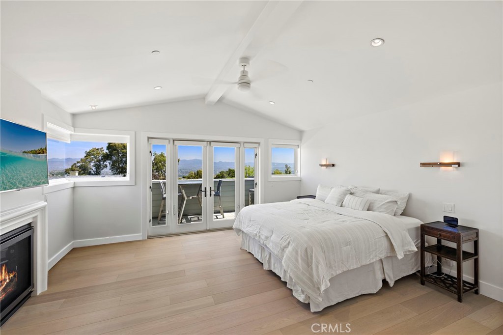 The primary suite is a true retreat, highlighted by vaulted ceilings, a fireplace, private balcony, and picture windows - 3203 Tyrol Drive, Laguna Beach CA 92651 - photo 19