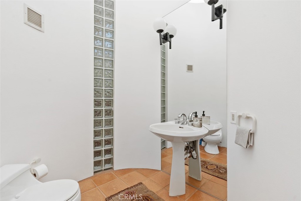 Half bath on top level off foyer entryway, has skylight in ceiling, glass block accents. - 664 Mystic View, Laguna Beach CA 92651 - photo 35