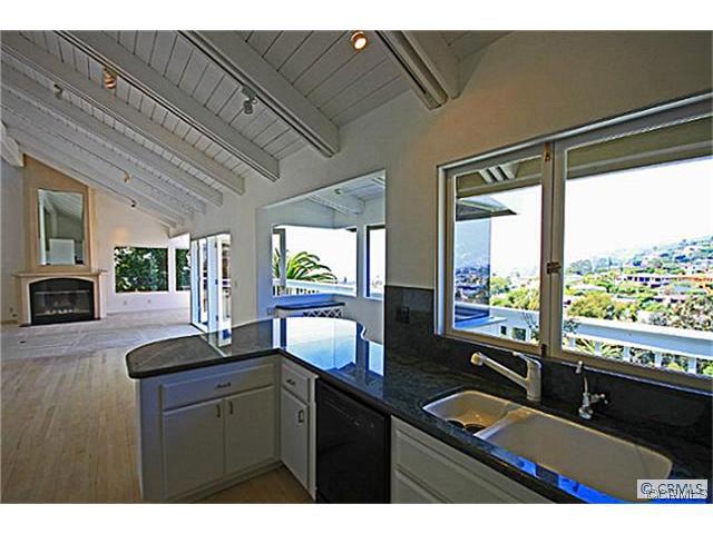 Kitchen open to living area featuring hardwood floors and wood burning fireplace. - 665 Temple Hills Drive, Laguna Beach CA 92651 - photo 1