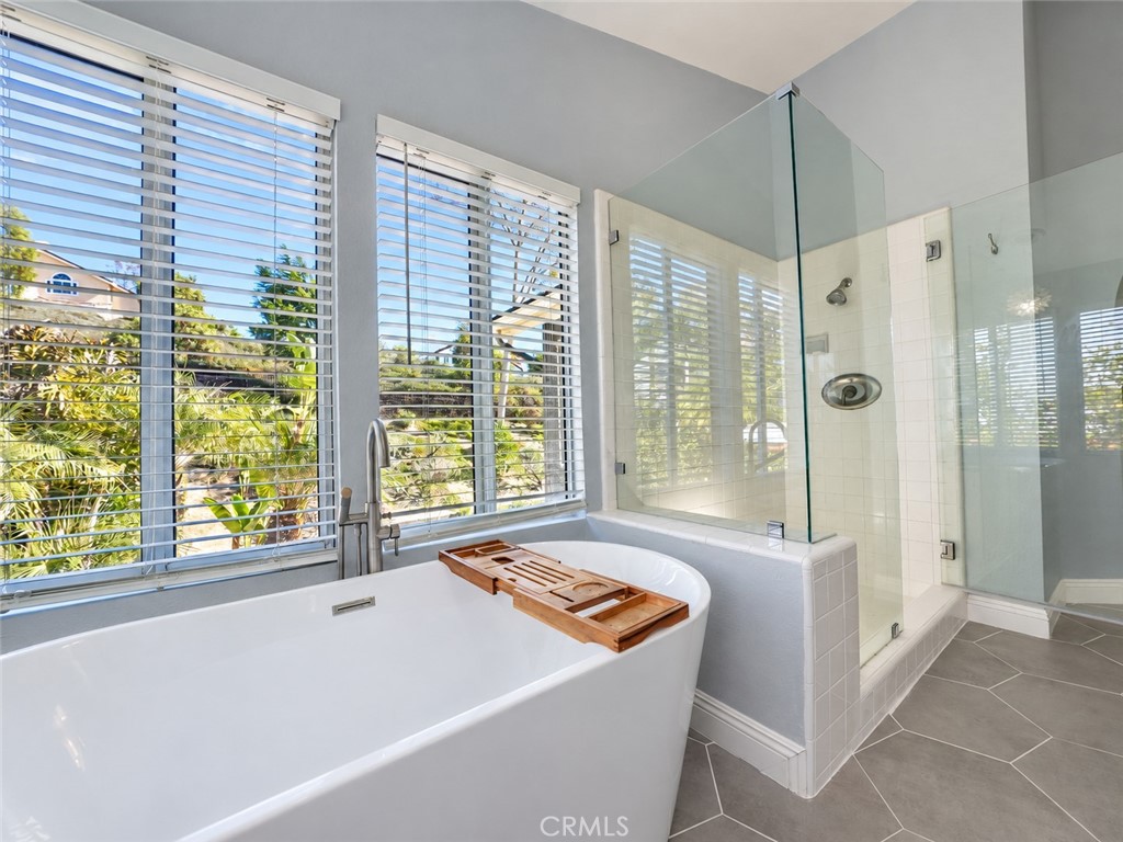 Luxurious primary bath with a walk-in shower, soaking tub, and dual-sink vanity - 25652 Nottingham Court, Laguna Hills CA 92653 - photo 21
