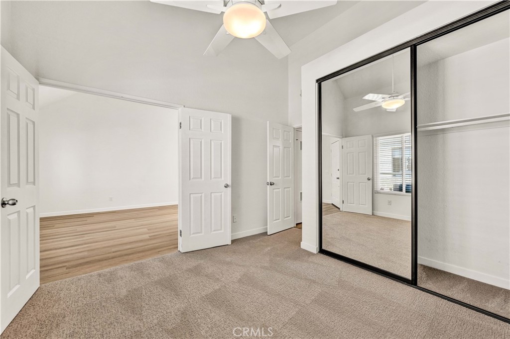 Double door entry into the guest bedroom, featuring a ceiling fan, mirrored closet doors, and newly installed carpeting. - 22 Aruba, Laguna Niguel CA 92677 - photo 12