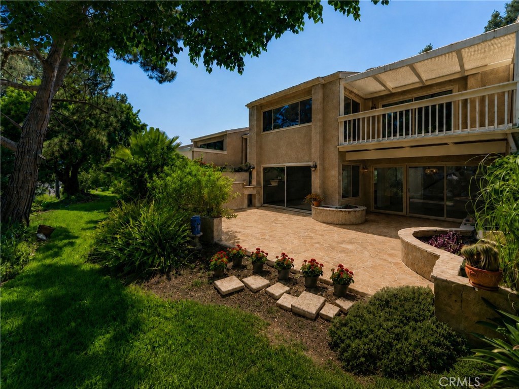 Rear exterior and landscaped outdoor living area with spacious patio, mature trees, and upper-level balcony. - 24356 Hillview, Laguna Niguel CA 92677 - photo 30